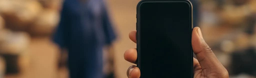 Une main tient un téléphone affichant le tableau de bord Ligdi Trust au marché.